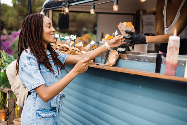 Happy African American girl buying fast food at the food truck stock photo