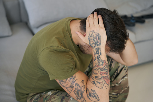 Militar agarrando la cabeza con las manos mientras sufre de TEPT photo