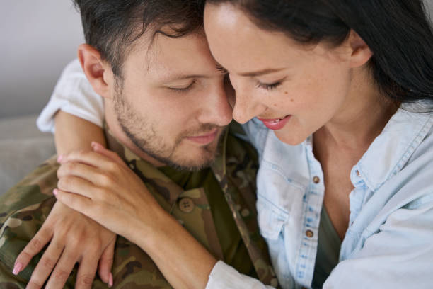 Man in the military brushing his forehead with woman while sharing loving moment with her