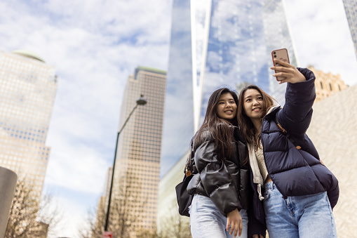 Two asian female tourist taking a selfie in front of the One World Trade Center. Lower Manhattan, New York