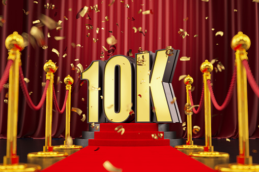 10K Celebration Neon Sign on a Podium with Red Carpet and Confetti. 3D Render