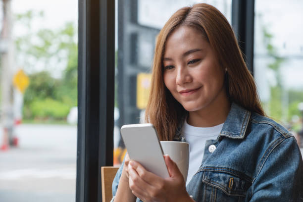 istock Portrait image of a young woman holding and using mobile phone while drinking coffee in cafe 1412209894
