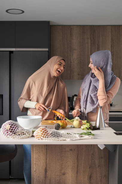 istock Two muslim women laughing while chopping and peeling vegetables at kitchen. 1412210539