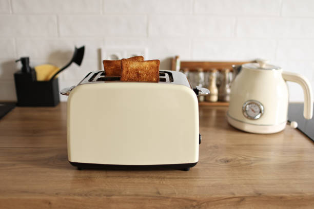 istock Modern white toaster and roasted bread slices toasts inside on wooden table in kitchen 1412214840