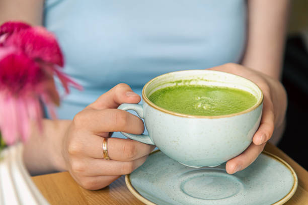 istock Close-up, a cup with green matcha drink in female hands. 1412215519