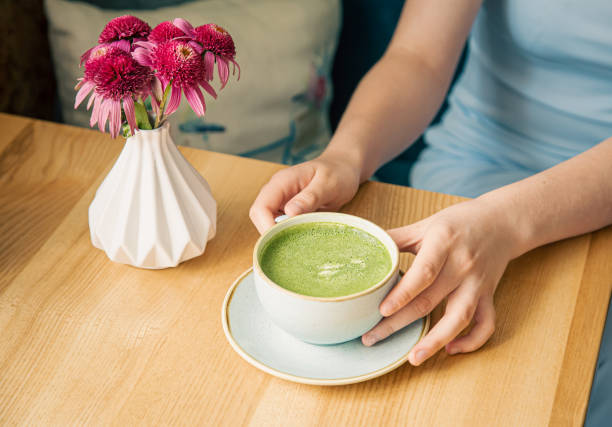 Close-up, a cup with green matcha drink in female hands. stock photo