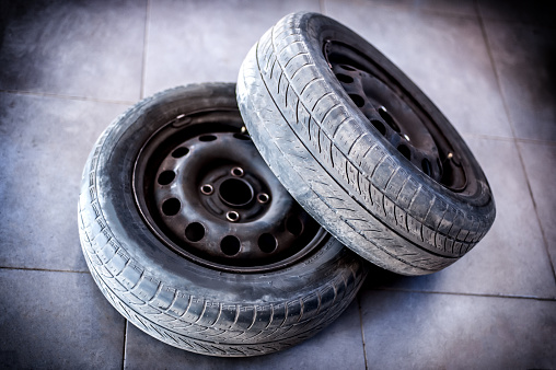 Two used car tires with wheels on the gray floor of the workshop