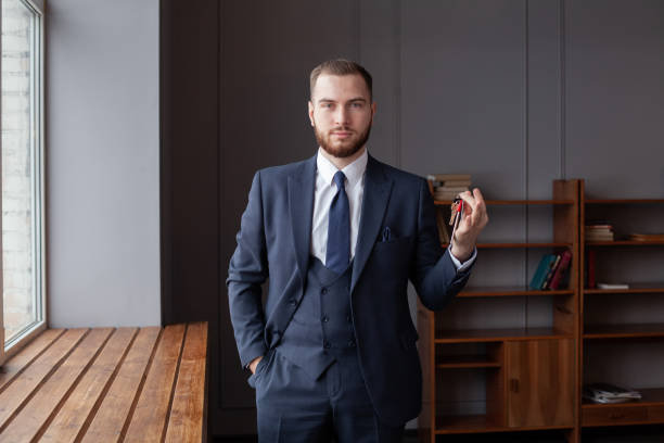 istock Serious confident businessman holding house keys in office. 1412217824