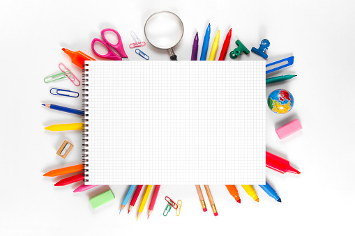 Directly above view of school supplies under notepad over white background