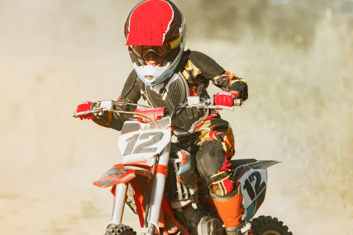 Male portrait of motocross enduro rider outdoors. Sports concept for motorsport on sports track. Professional biker with helmet and stunt motorcycle. Man with protective sportswear.