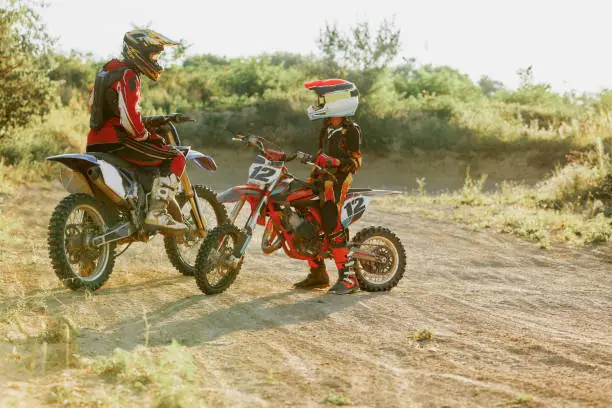 Tips and tricks. Live shot of junior sportsman, motorcyclist training on motorbike at hot summer day, outdoors. Motocross sport, competition, male hobby, energy and ad