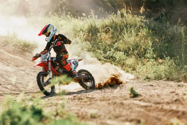 Speed and energy. Live shot of junior sportsman, motorcyclist training on motorbike at hot summer day, outdoors. Motocross sport, competition, male hobby, energy and ad