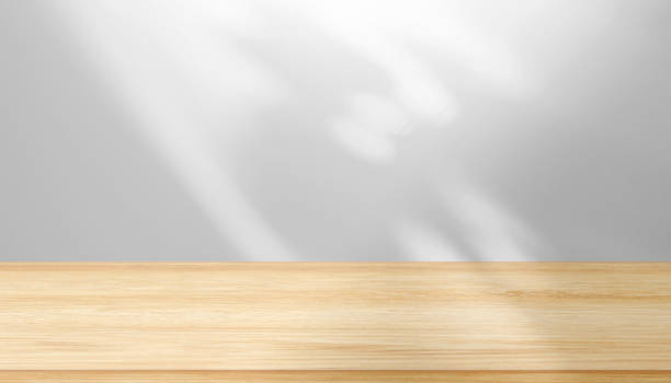 istock Blank brown table top, shelf in front of wall with abstract shadows, light 1412220030