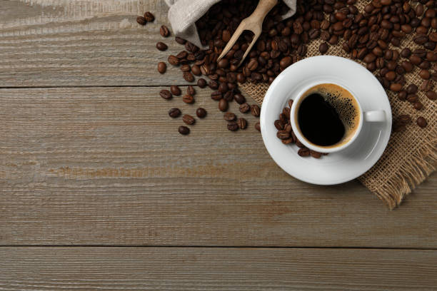 istock Cup of aromatic hot coffee and beans on wooden table, flat lay. Space for text 1412220842