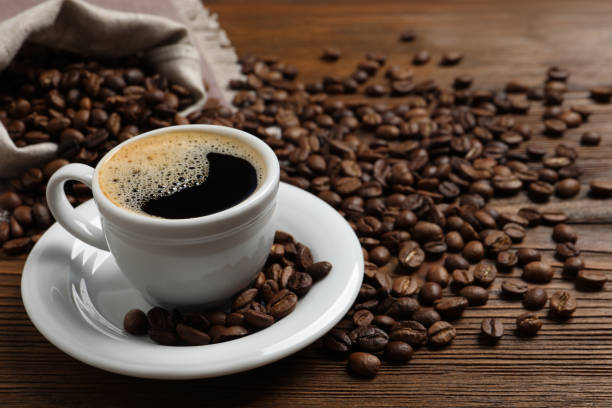 istock Cup of aromatic hot coffee and beans on wooden table, space for text 1412220898