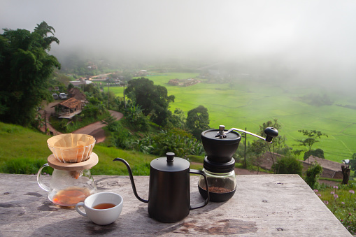 Drip coffee set on wooden table with foggy morning and rice field background, Set for make coffee drip