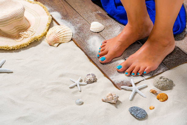 Close up of woman feet standing on white sand beach.