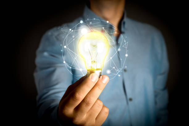 istock Glow up your ideas. Man holding light bulb on black background, closeup 1412223252