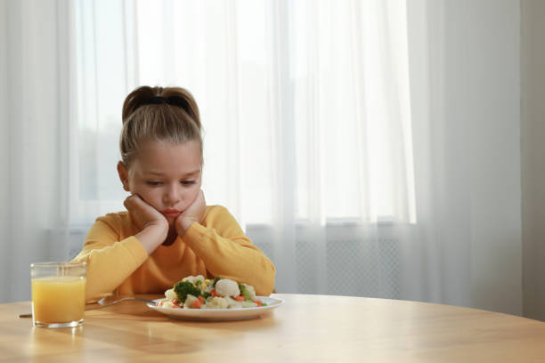 istock Cute little girl refusing to eat vegetable salad at home, space for text 1412225741