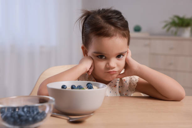 istock Cute little girl refusing to eat her breakfast at home 1412225851