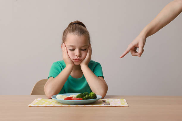 istock Cute little girl refusing to eat her breakfast at table on grey background 1412225864
