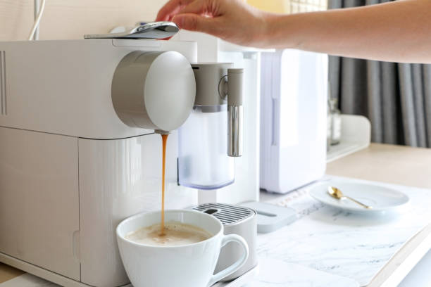 istock A hand using a coffee maker machine to brew an espresso coffee. Coffee being poured into white mug. A modern home/office coffee machine appliance 1412229623