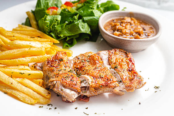 A white dish of chicken breast grilled with french fried and fresh dressing salad stock photo