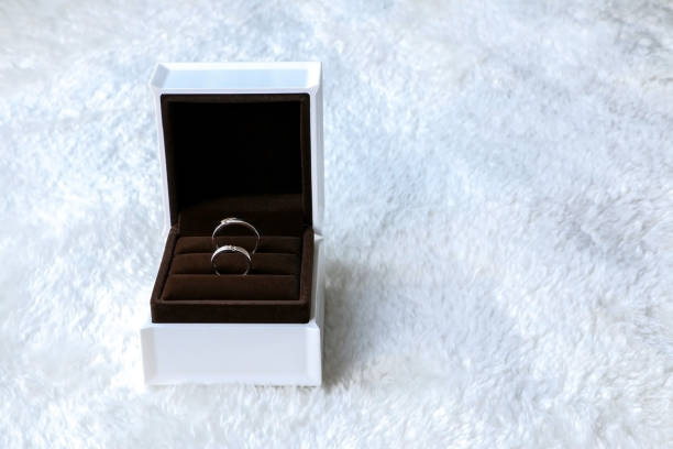 istock Two beautiful wedding rings displayed in open box on left side, isolated on white fur background, concept of romance, love and marriage 1412232109