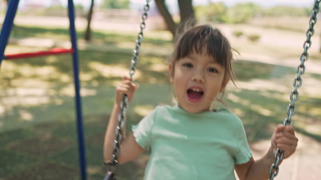 Smiling girl playing on the swing