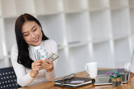 Happy Asian beautiful woman holding banknotes counting cash happily.