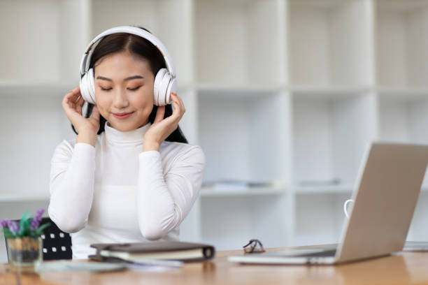 Attractive beautiful Asian woman wearing headphones enjoying listening to music. stock photo