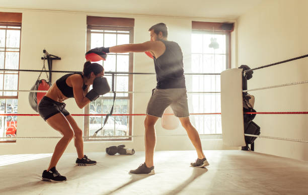 istock Young boxer ducking a strike from her personal trainer in a boxing ring 1412234023