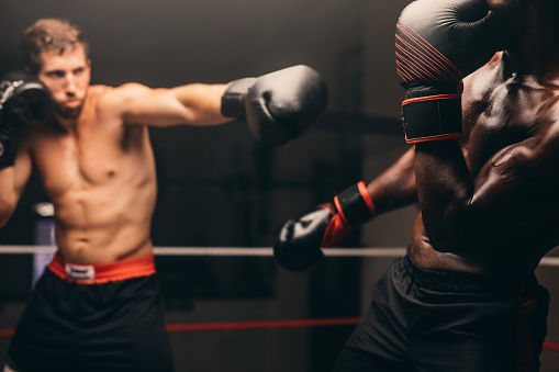 One man, handsome male boxer training alone in fighting ring.