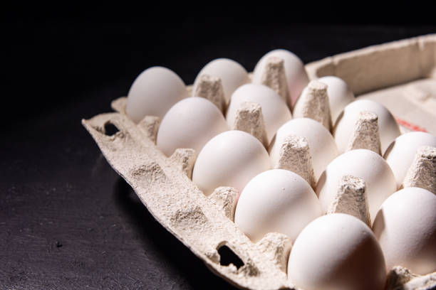 istock Chicken white eggs on a black background. Farm products. Natural eggs. Chicken eggs on the table. Chicken eggs in a cardboard box 1412236001