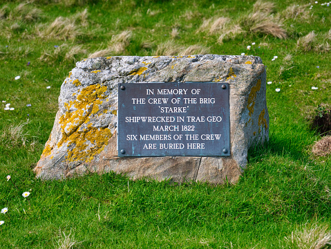 A rectangular plaque attached to a rock marks the graves of six of the crew who died when the brig Starke was shipwrecked near by in 1822.