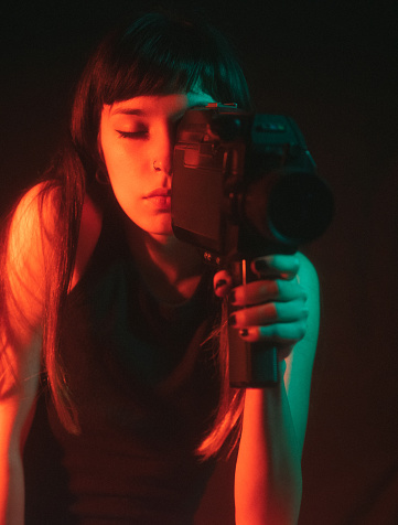 Portrait of young woman with vintage movie camera