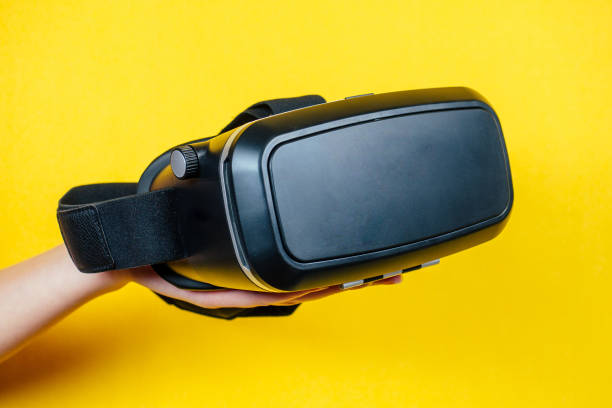 istock hand holds a virtual reality helmet ( glasses ) on a yellow background 1412240112