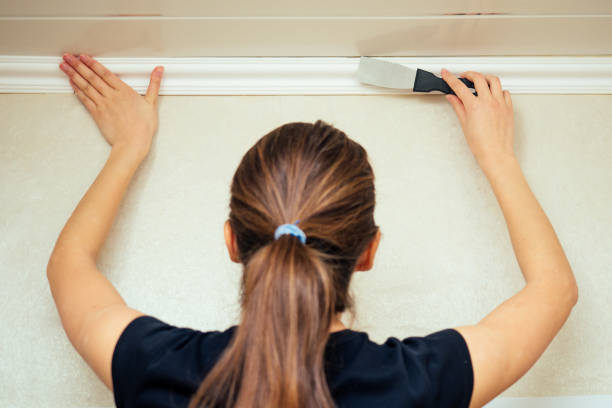 istock girl (woman) working in a black T-shirt is installing a plinth on the ceiling 1412240224