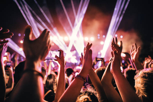 Rave party. Rear view of large group of people enjoying a concert performance.  People in foreground are released. music festival stock pictures, royalty-free photos & images