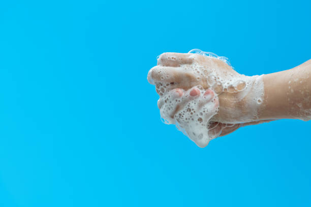 Washing hands with soap on blue background.