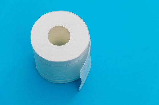Roll of white toilet paper on blue background.