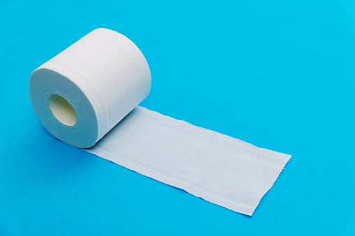 Roll of white toilet paper on blue background.