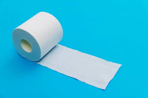 Photo of Roll of white toilet paper on blue background