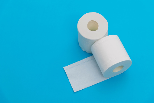 Two rolls of white toilet paper on blue background.