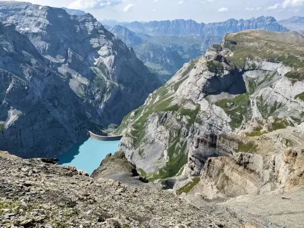 Kistenpass hut. View of the Limmernsee dam in the canton of Glarus. Hiking high above the mountain lake in the Alps
