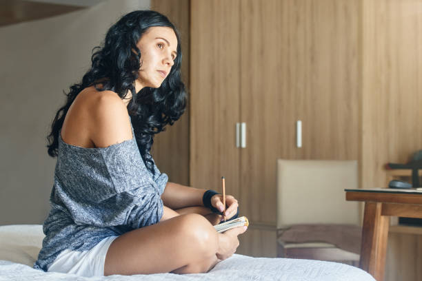 istock Young pensive woman artist draws with a pencil in notebook 1412245708