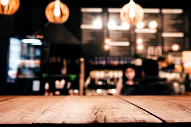 Background with wooden old deck table in front of blurred in bar or restaurant Empty blank wooden old deck table in front of abstract blurred festive background in bar, cafe, pub or restaurant with light spots and bokeh for product montage display of product. Copy space area pub table top view stock pictures, royalty-free photos & images