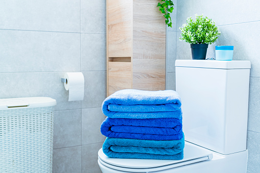 Folded blue towels placed on a modern bathroom toilet. High resolution 42Mp indoors digital capture taken with SONY A7rII and Zeiss Batis 40mm F2.0 CF lens
