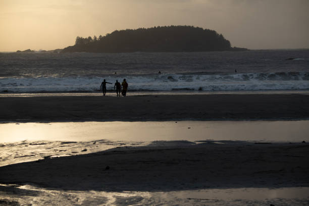 Surfers strolling beach at sunset in Tofino BC in Tofino, British Columbia, Canada