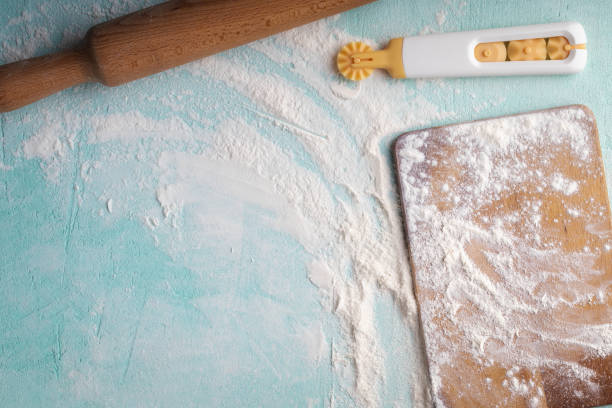 istock Rolling pin, cutting board, dough cutter with flour on blue background. Bakery accessory. With copy space, top view 1412248923